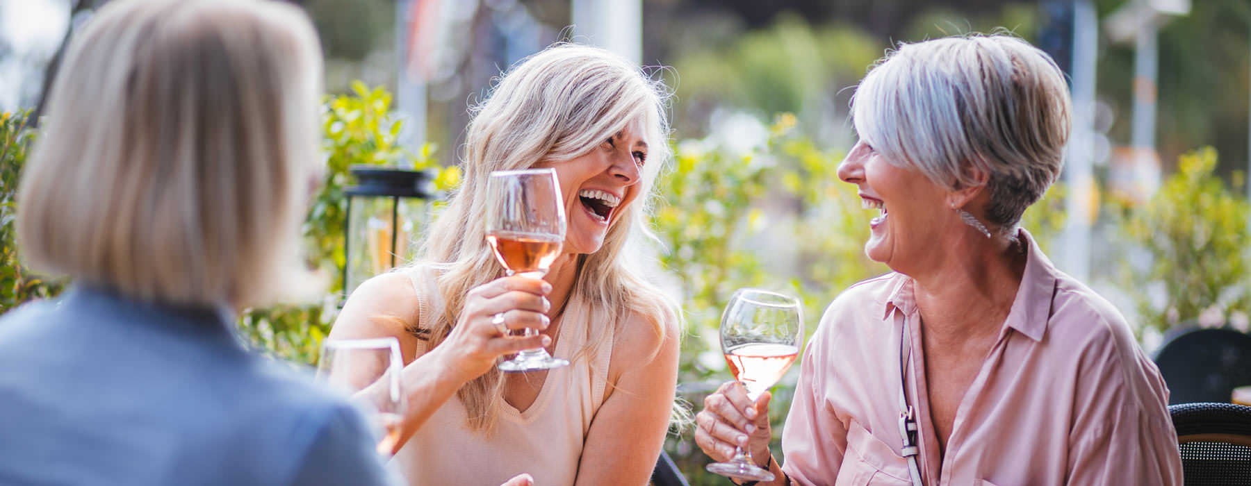 Lifestyle photo of women raise glasses of wine outdoors