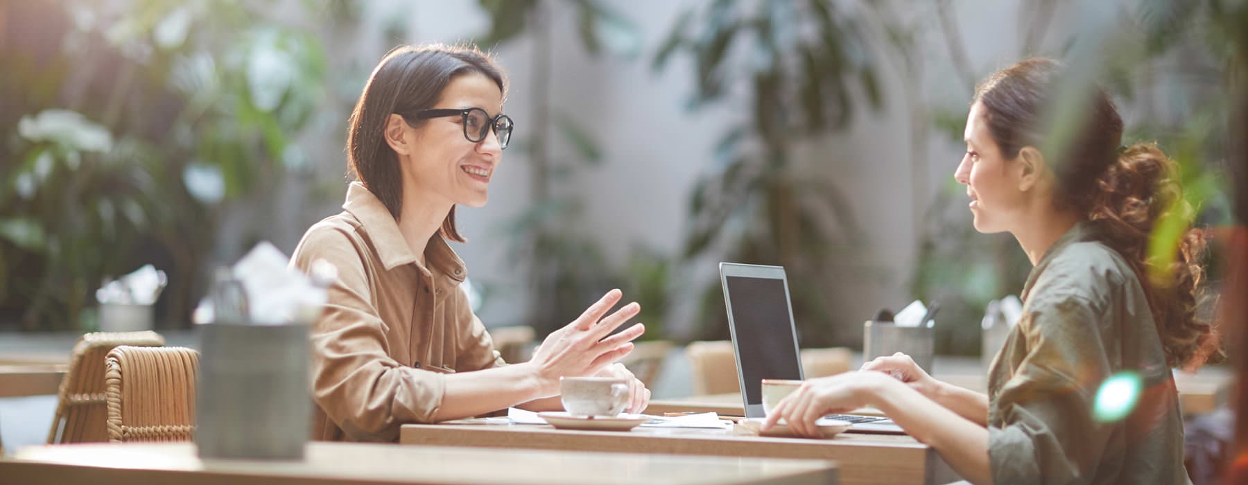 two women talk business over coffee at outdoor restaurant table